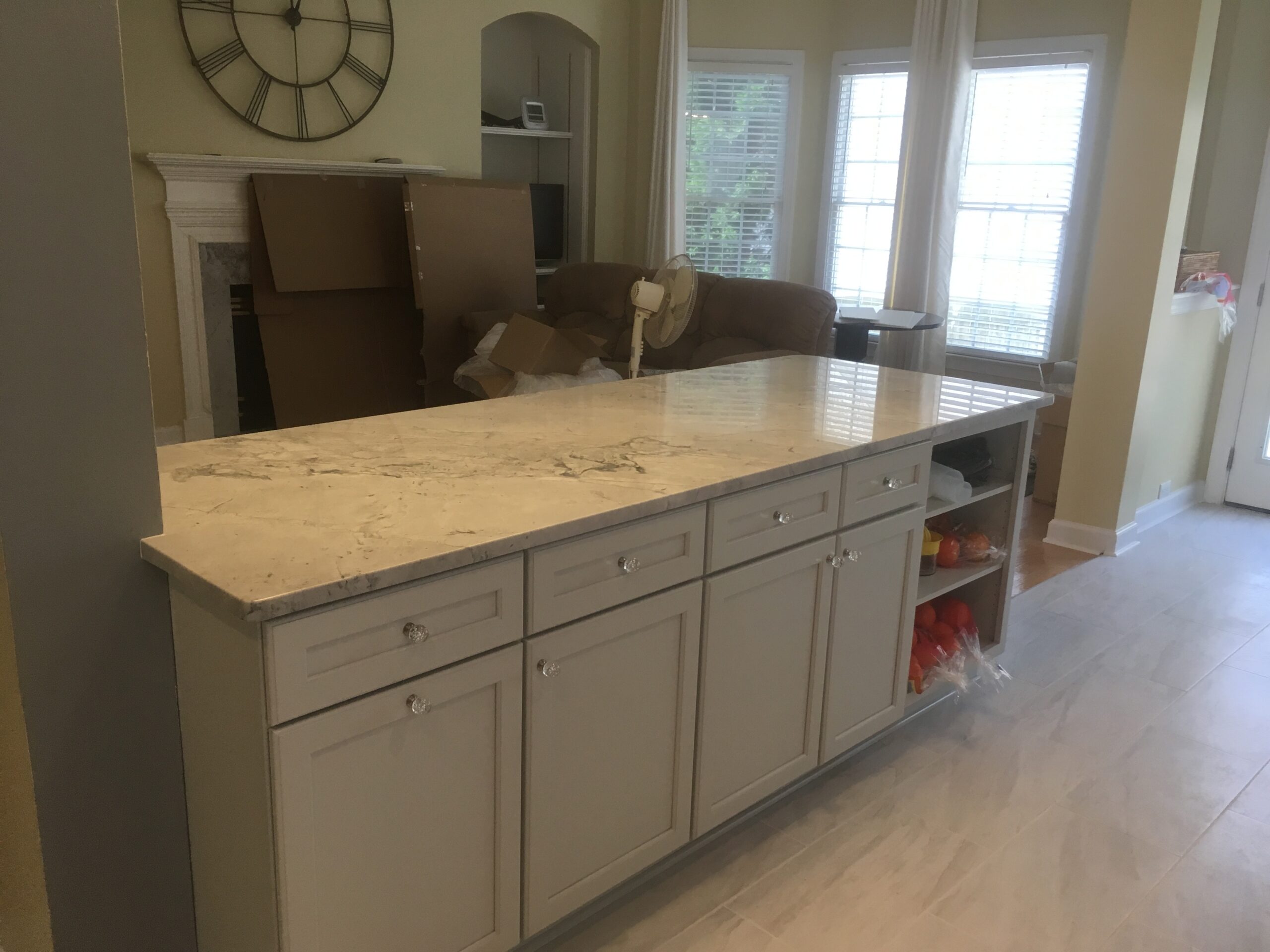 Waterfall quartz island opening onto an adjoining living room with fireplace
