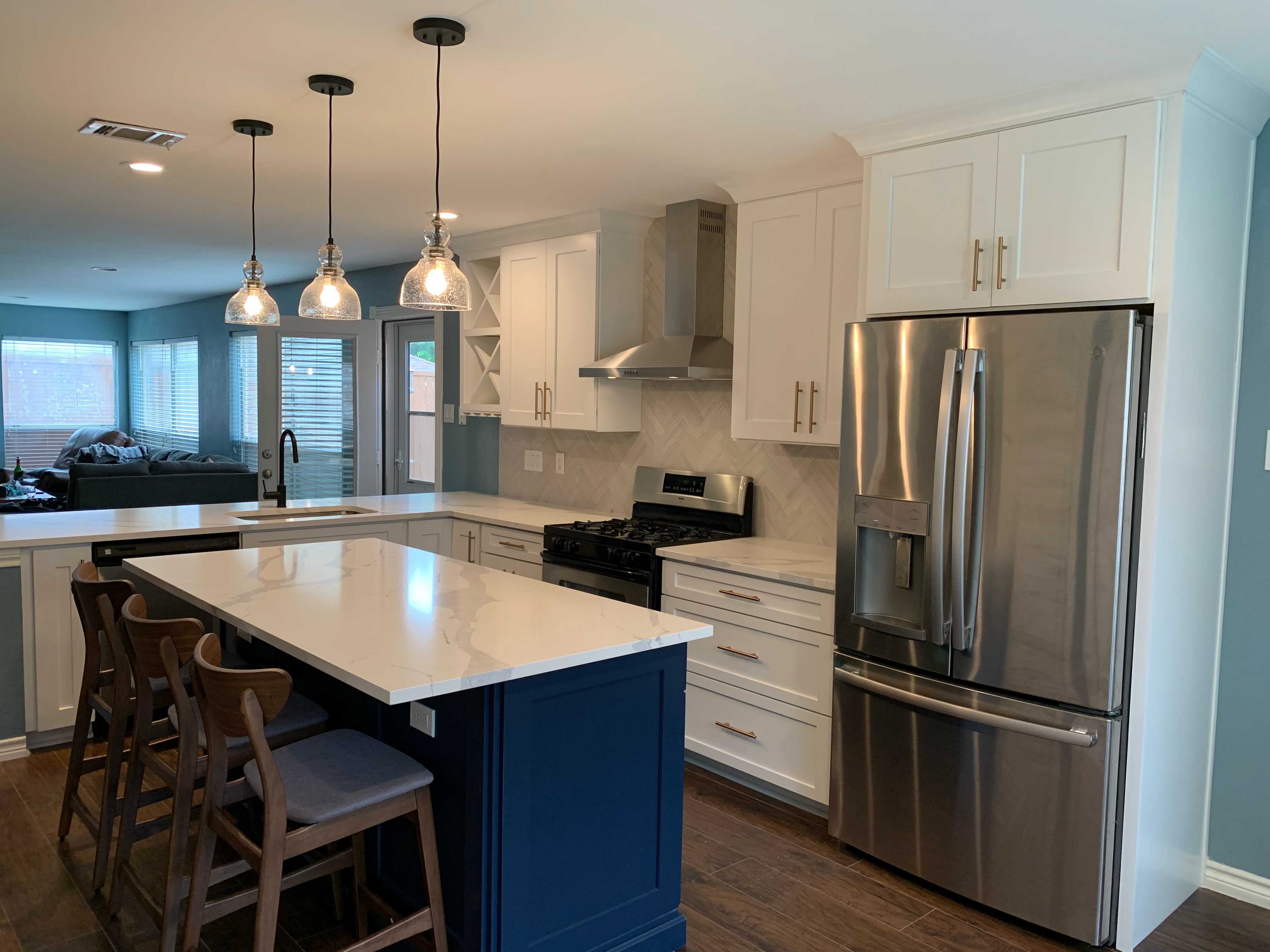 Navy blue kitchen island with quartz countertop and wood bar stools