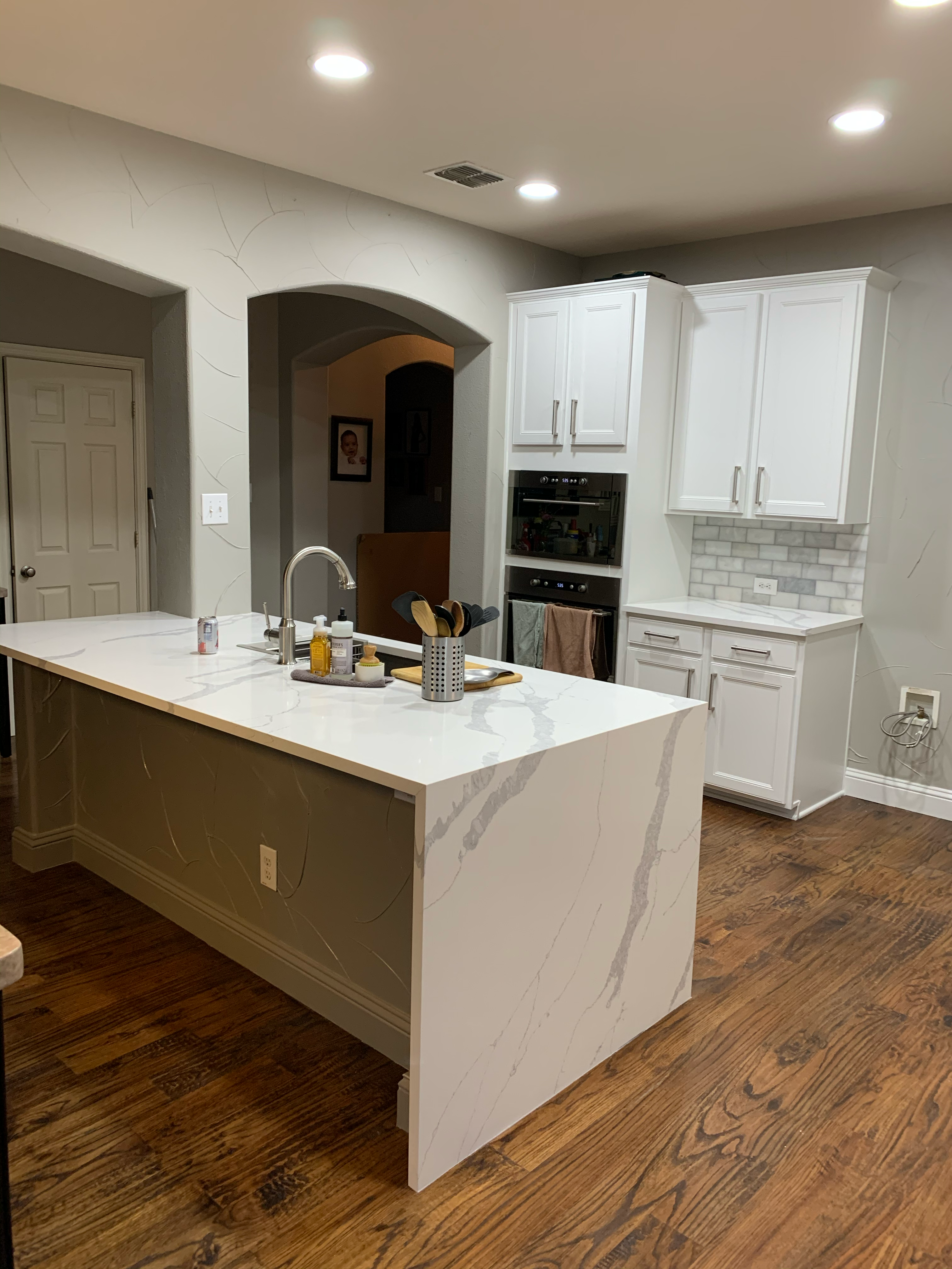 Quartz waterfall island with undermount sink and hardwood flooring