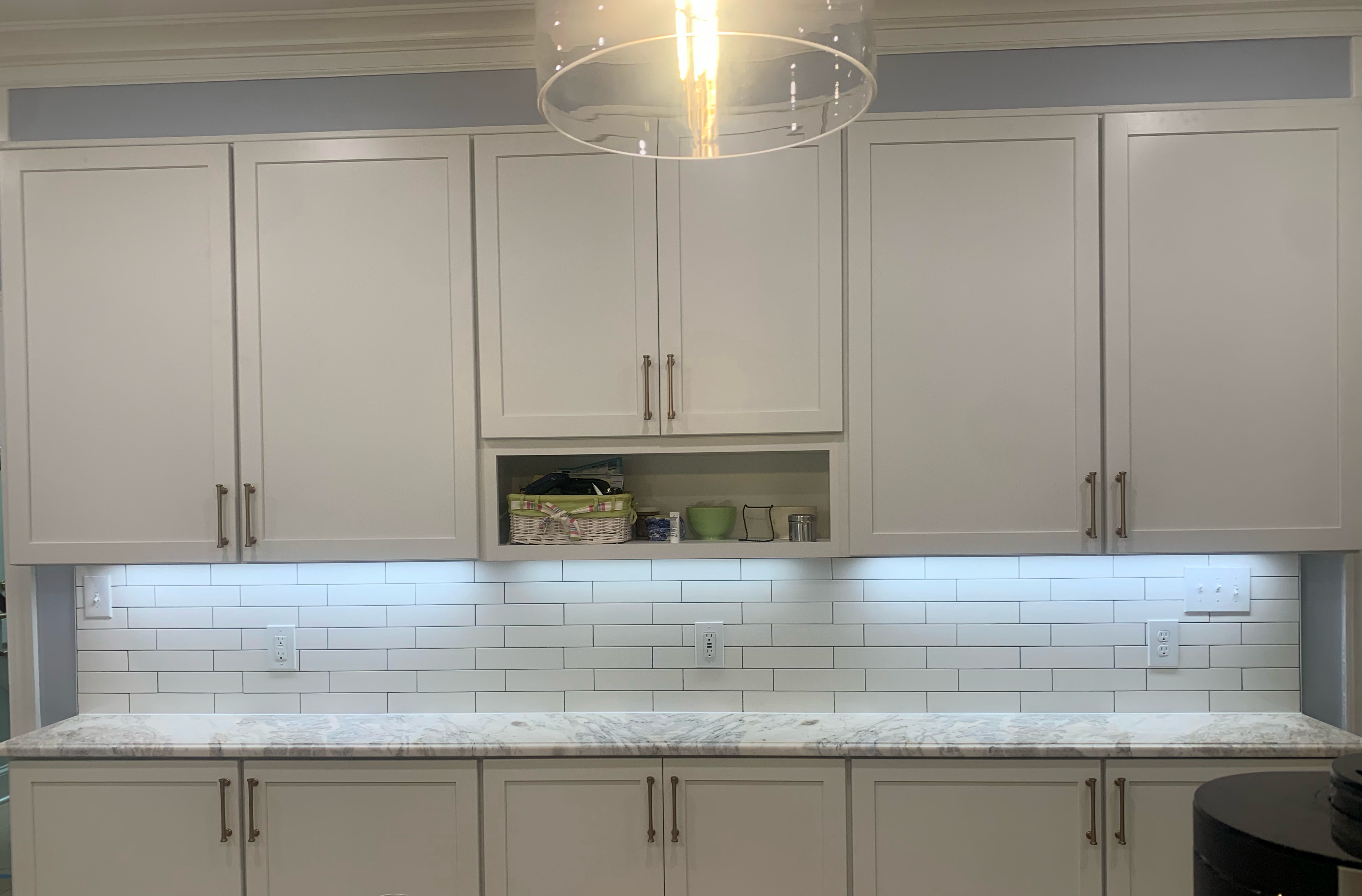 Full view of a bright white kitchen with arched window and marble-look counters