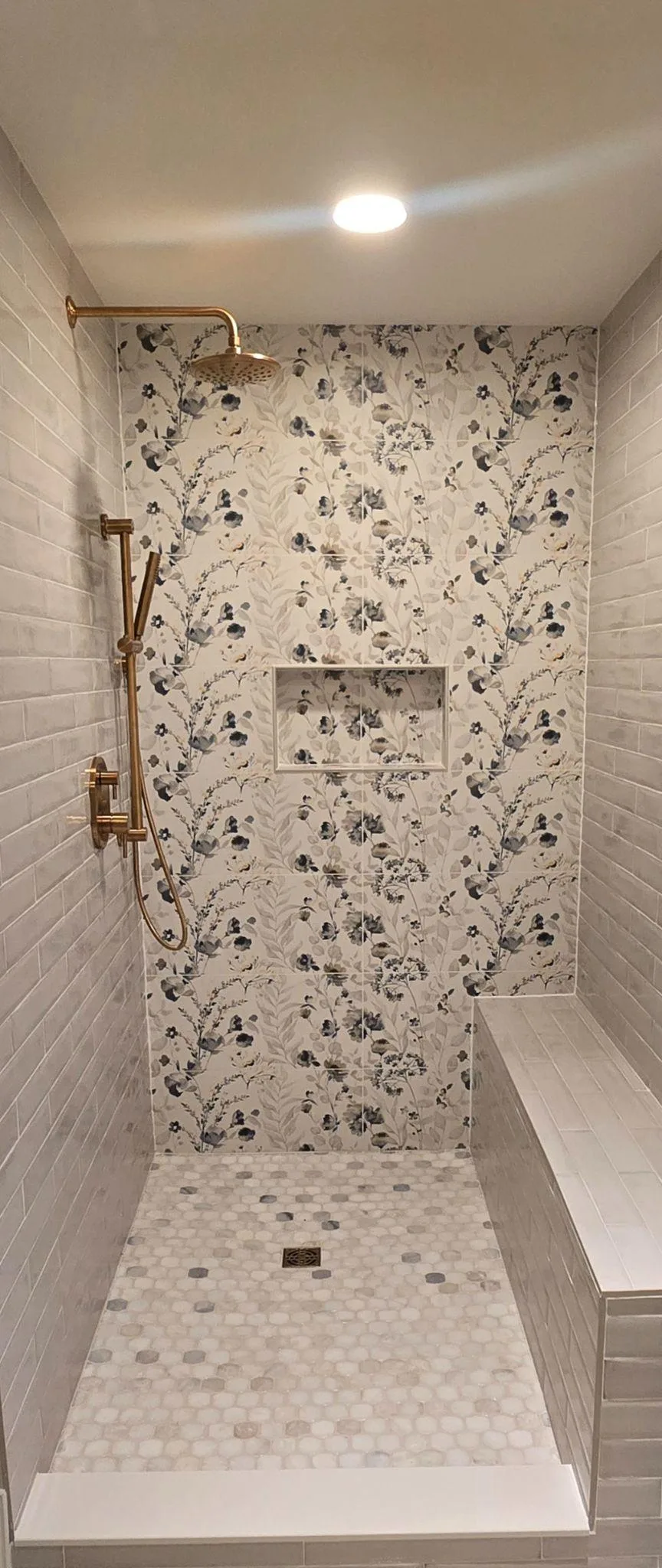 Walk-in shower with patterned tile and recessed niche in a small bathroom